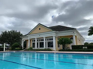 A neighborhood clubhouse with a colonnaded porch overlooking the community pool.