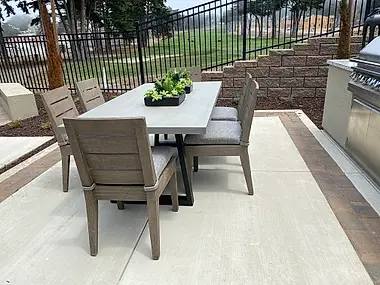 An outdoor dining table set for six, centered with a low succulent arrangement.