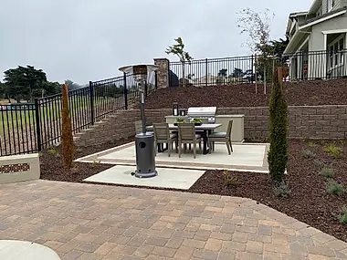 A terraced backyard patio with a built-in grill station and a freestanding patio heater.