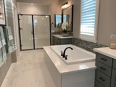 A hallway vignette with a dark wood dresser, a round mirror, and a fresh orchid between two ensuite doors.