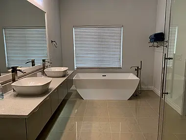 A primary bath with dual vessel sinks, a freestanding tub, and a glass-enclosed shower.