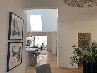 A skylit passage between the entry and an open kitchen island, framed by a gallery wall of abstract prints.