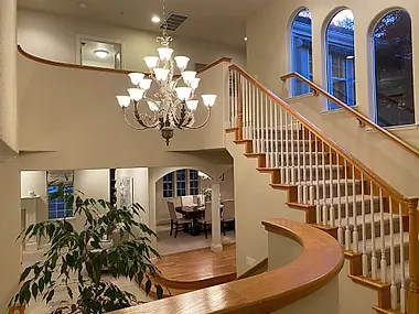 A two-story foyer under a tiered crystal chandelier, opening onto the dining room beyond.